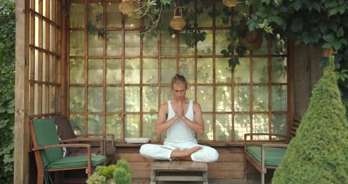 Young Adult Meditating in a Garden Gazebo