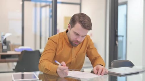 Man Signing Document in Office Setting
