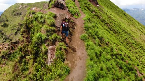 Young Adult Hikes Up Tropical Mountain Trail