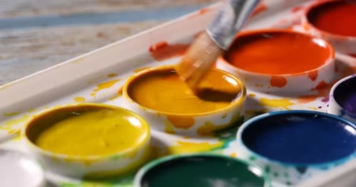 Painting with brush and watercolor at wooden table, closeup