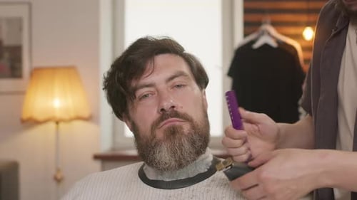 Barber Trimming Man's Beard with Clippers
