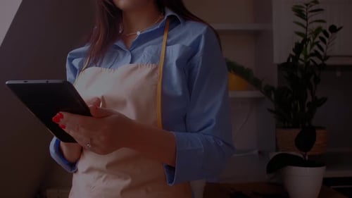 Female florist with tablet taking notes about plants, gardening Concept of digital plant, horticultu