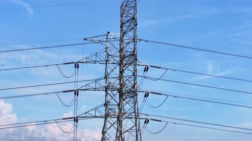 Industrial power pylons in open landscape with blue sky,