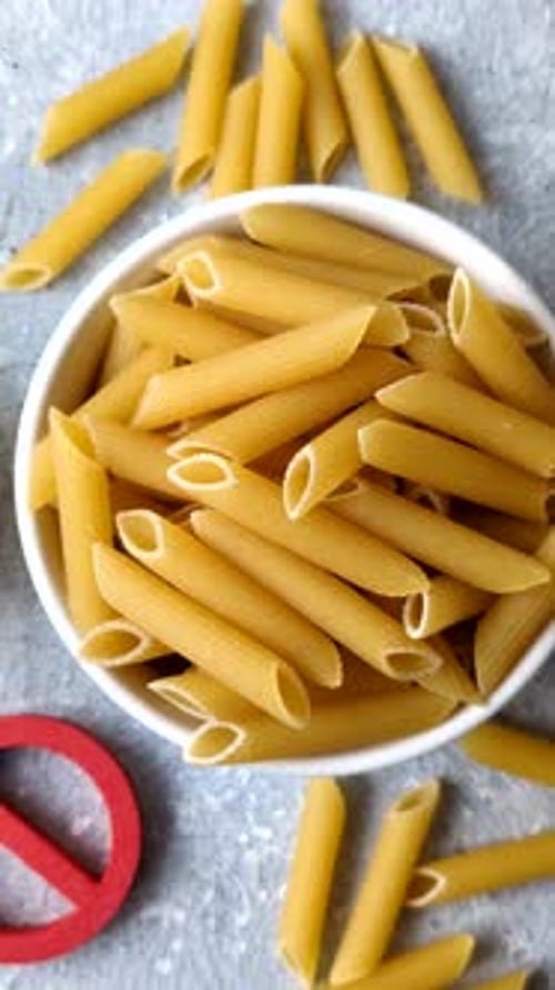 Italian uncooked dry penne regatta pasta with a gluten prohibition sign. The gluten prohibition sign