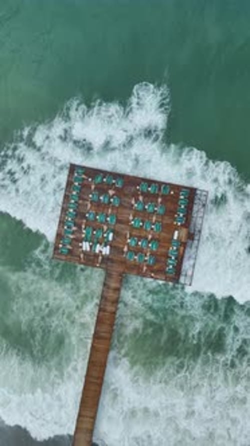 Vertical Video of Pier With Umbrellas Above Calm Water and Gentle Moving Sea Surface Texture