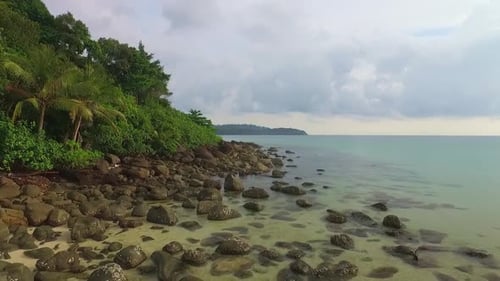 Aerial drone dolly shot of rocks on a tropical Thai island with jungle and clear ocean in Koh Kood,