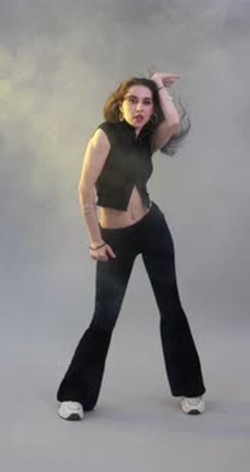 Junge Frau tanzt Hip-Hop-Tanz im Rauch auf grauem Hintergrund