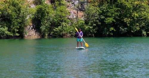 Portrait Of A Man Stand-up Paddleboarding Over The Mreznica River In Croatia. Aerial Shot