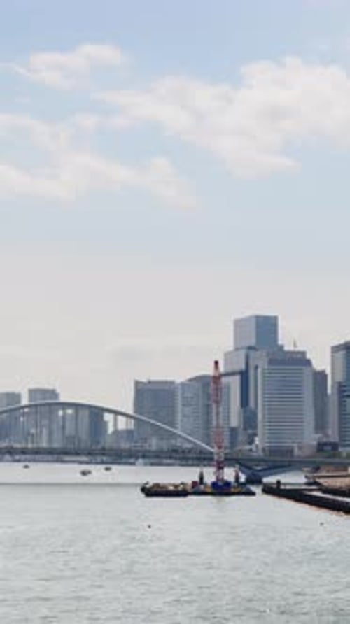 View of the Kachidoki Bridge with the buildings in Chuo, Japan on the background in daylight. Vertic