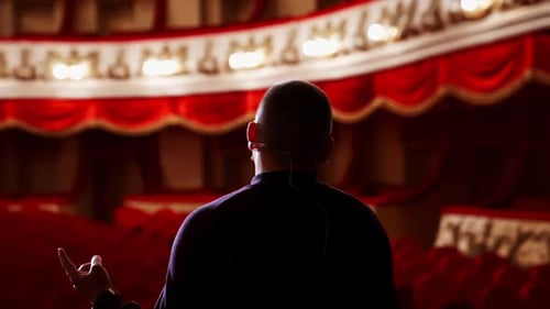 Actor rehearsing in front of empty auditorium.