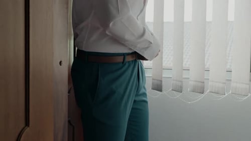 Man Adjusts Belt Wearing Shirt and Slacks