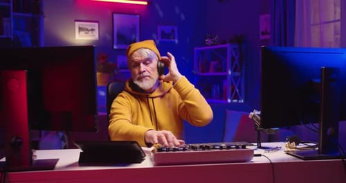 Senior Man Working on Audio Mixing Board at Desk