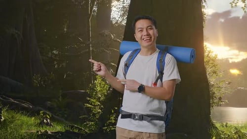 Asian Male Smiling And Pointing To Side While Exploring Nature