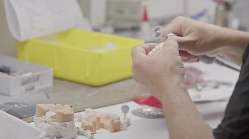 Adult Hands Shaping Dental Prosthetic in Clinic
