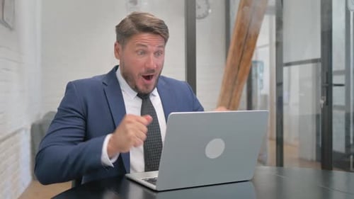 Excited Businessman Celebrating Success in Office Environment