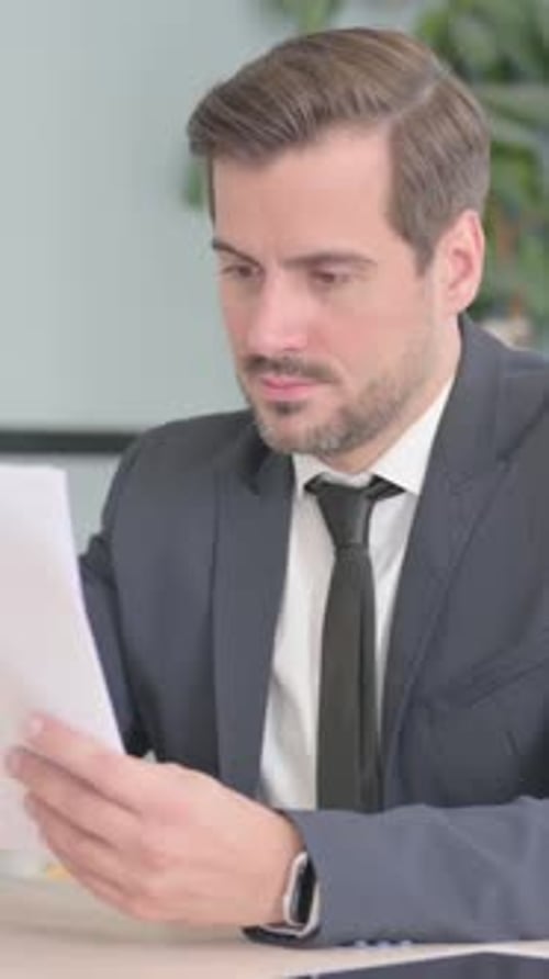 Man in Suit Reads Documents in Office Setting