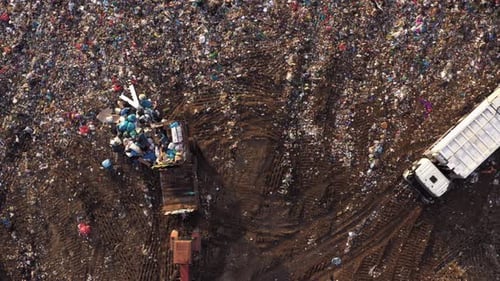 Top View of Tractor Dumps Garbage on the Landfill