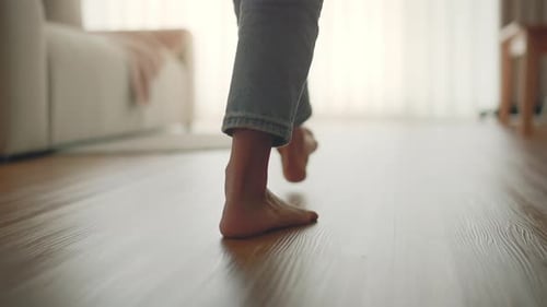 B roll - Closeup foot of young woman walking on wooden floor at home