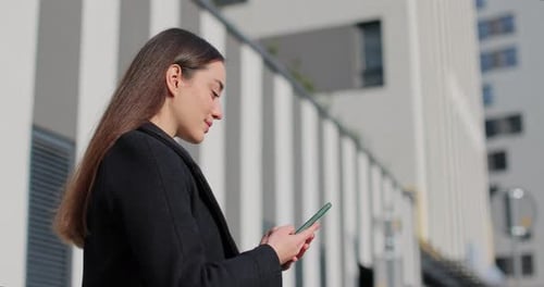 Woman Uses Phone Near Modern Building