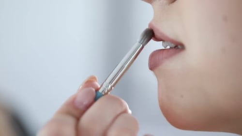 Artist doing beautiful makeup on woman's face indoors, closeup