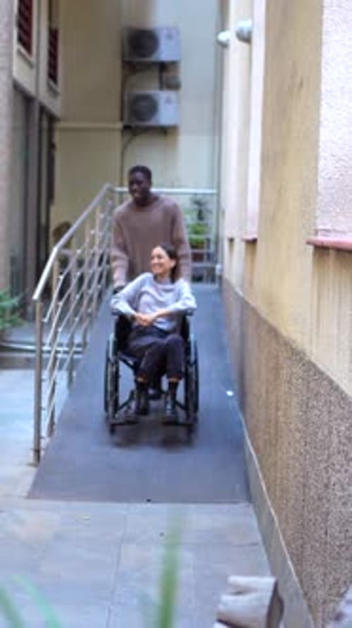 Woman in Wheelchair on Ramp, Man Pushing