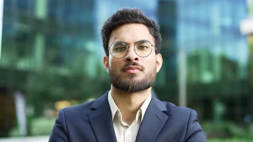 Portrait of a confident businessman in suit standing on the street near a business office building.