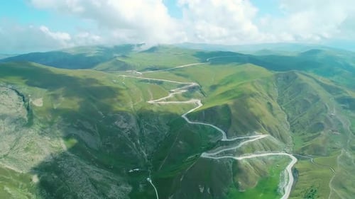 Aerial Over Winding Asphalt Road Among Mountains Covered with Green Grass in Highlands of Caucasus