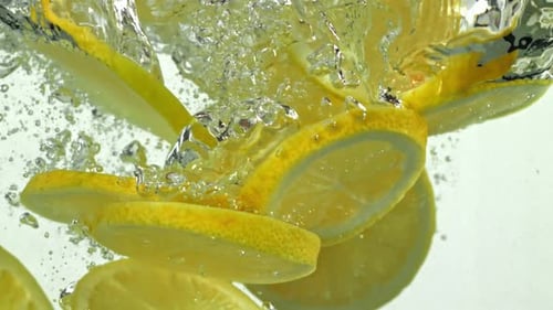 Lemon Slices Falling into Clear Water, Bubbles Rising