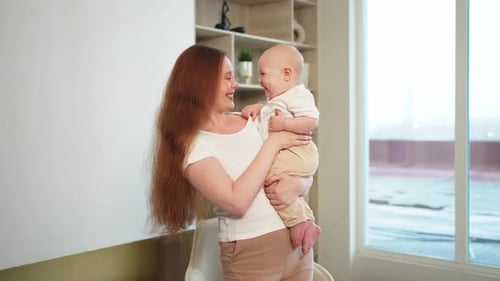 Smiling Mother Holds Happy Baby Indoors