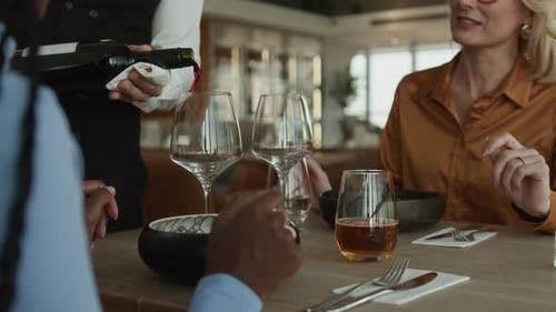 Waiter Serving Red Wine to Female Guests in Luxury Restaurant