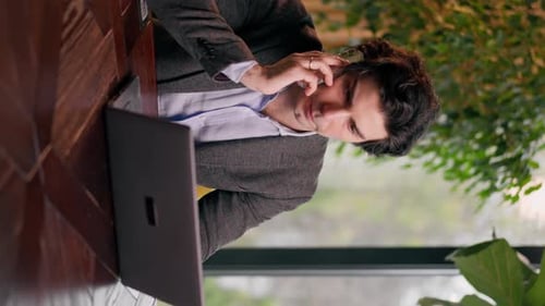 vertical video a serious man a businessman works at a laptop in the office communicates colleagues