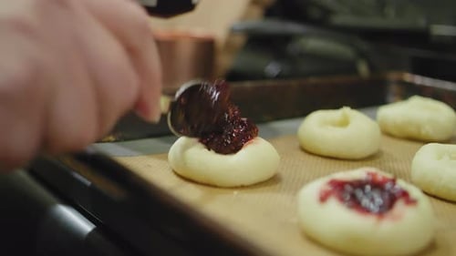 filling cookies full of jam with a spoon