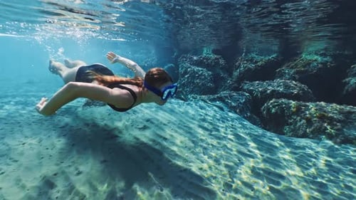 A Beautiful Girl in a Mask for Swimming Under Water Dives Into the Ocean