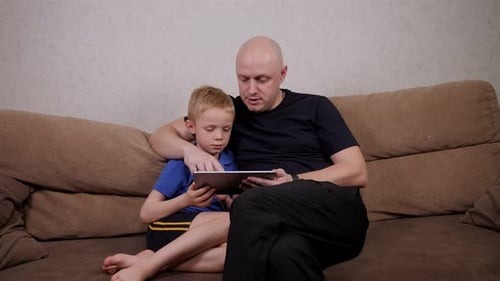Man and Boy Using Tablet Together on Couch