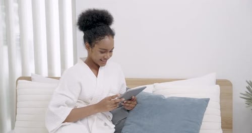 Young Woman Relaxing with Tablet in Bright Bedroom