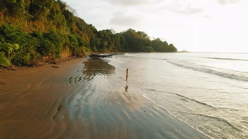 Solitary woman enjoying view of sandy beach ocean waves at dusk in Costa Rica