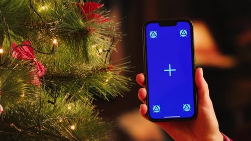 Closeup of Green Screen Phone Smartphone in Woman Hand on Red Christmas New Year Background Gifts