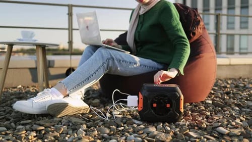 Mulher trabalhando no laptop sem parar devido à carga da estação de energia