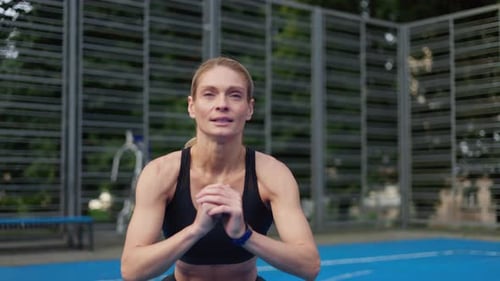 Sportswoman Doing Squat Exercises with Resistance Band on Street Stadium
