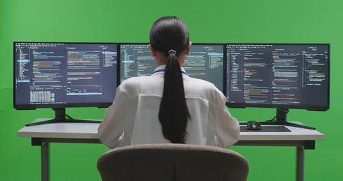 Asian Woman Developer Using Computer To Write Code With Multiple Screens In Green Screen Studio