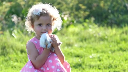 Girl Cradling Cute White Rabbit in Green Field