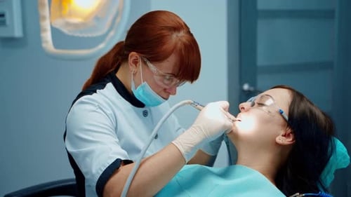 Woman Dentist Cleans a Woman's Teeth