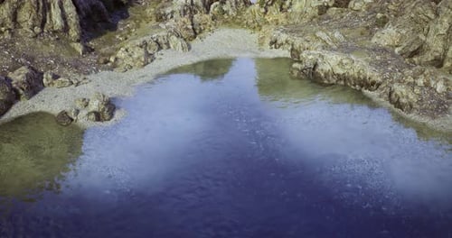 Tranquil Water Surface Reflecting Surrounding Rocky Landscape at Sunset