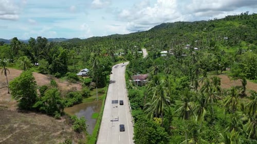 A View From Above of Barely Curved Road Passing Through Small Settlement with Small Houses and Green