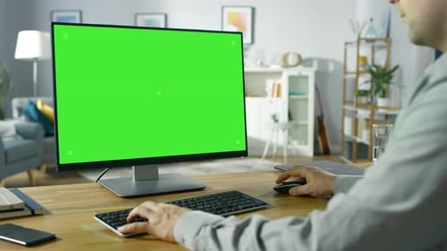 Over the Shoulder Shot of Professional Freelancer Working on Green Mockup Screen Personal Computer
