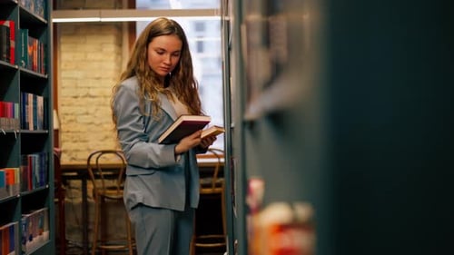 Young Woman Reading Book in a Library