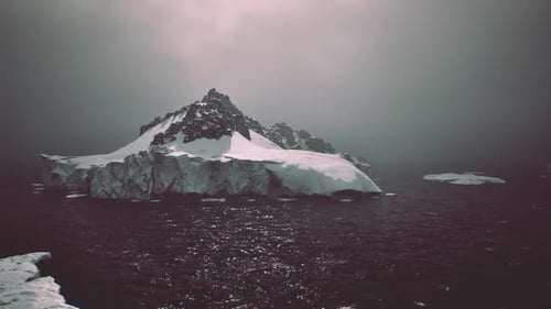 Einsamer Eisberg taucht durch dichten Nebel über dem ruhigen Meer auf
