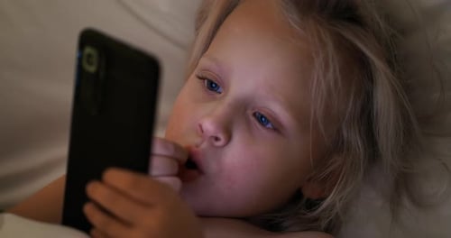 Child Lying in Bed, Using Phone at Night
