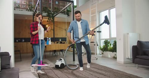 Couple Dancing With Vacuum and Mop at Home