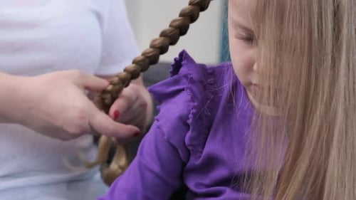 Young Loving Mother Brushing Kid Daughters Hair and Styling Hairdo Braid Hairstyle at Home